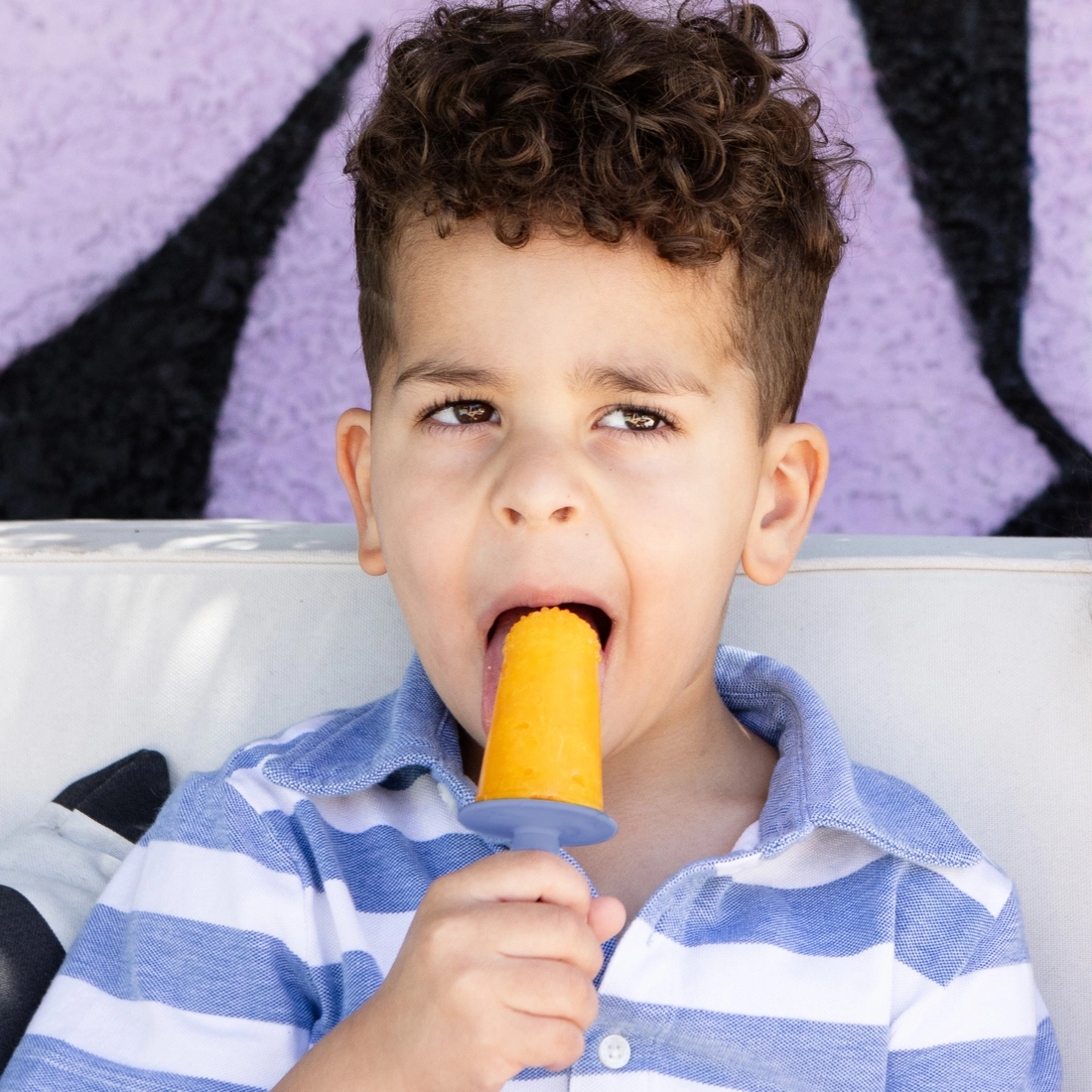 Child eating a popsicle against a colorful background
