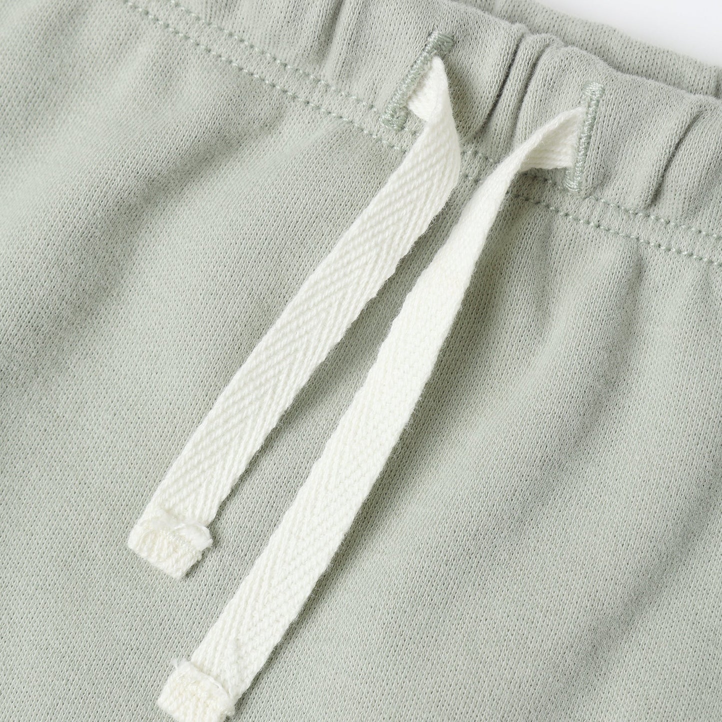Close-up of a fern green fabric with a white drawstring on a white background