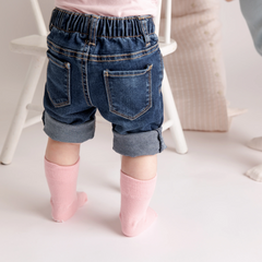 toddler legs in denim shorts with a pair of light pink socks on