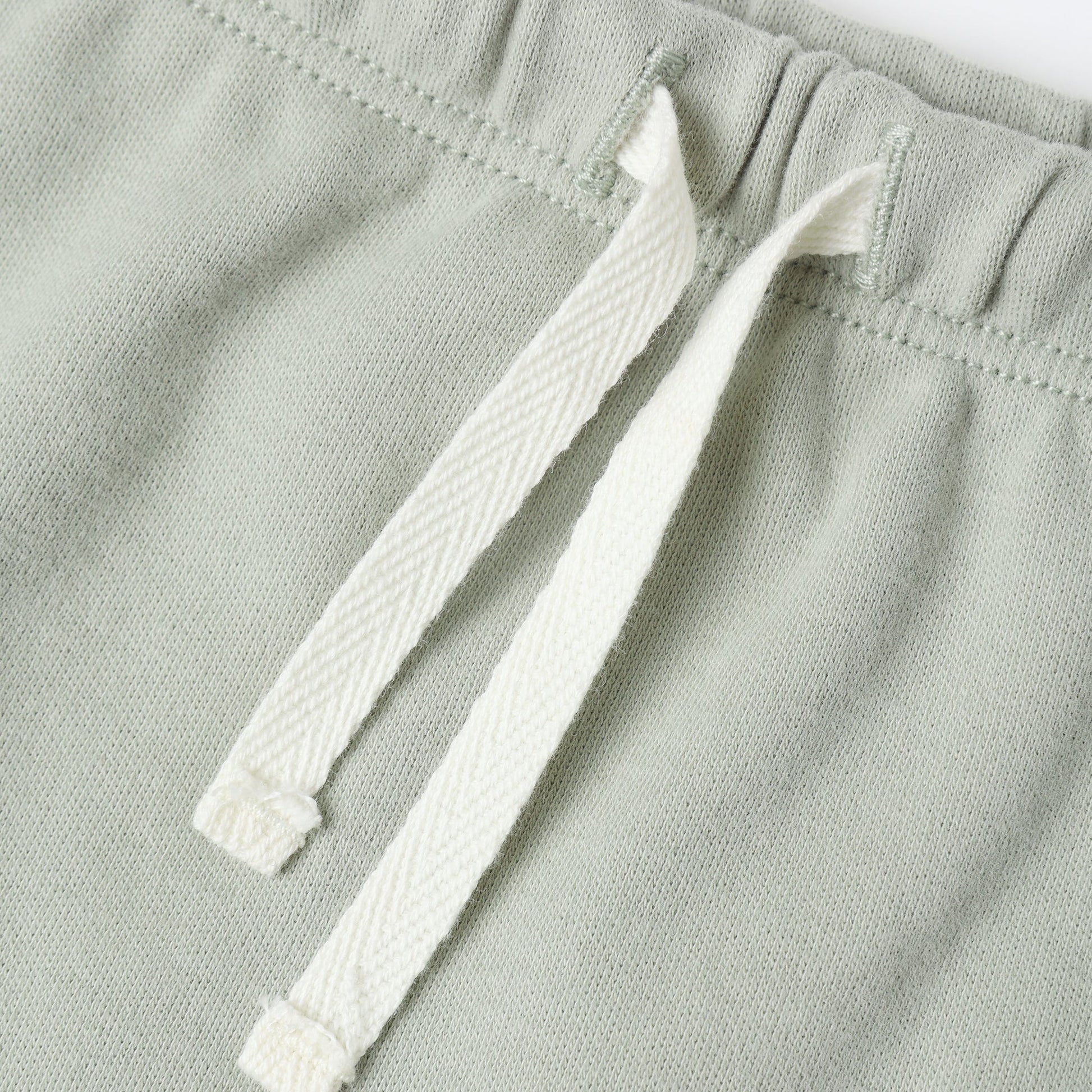 Close-up of a fern green fabric with a white drawstring on a white background