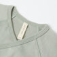 Close-up of a fern green baby outfit with a Quincy Mae label on a white background